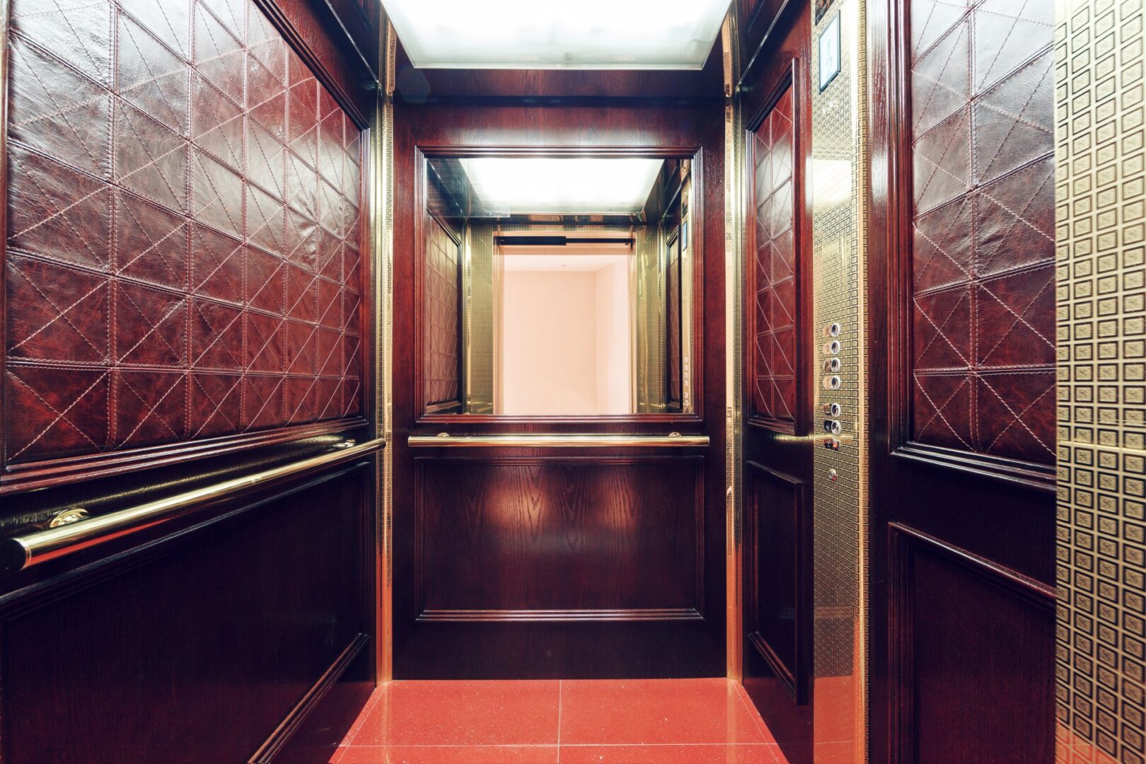 Custom elevator cab interior with walnut millwork panels and metal inlays by Manhattan Elevator Interiors